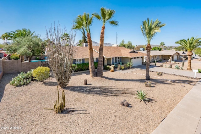 ranch-style home with a garage, fence, and concrete driveway