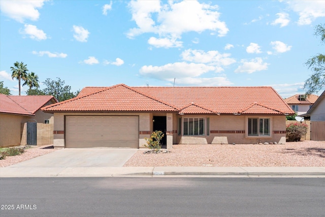 ranch-style home with an attached garage, stucco siding, a tiled roof, and driveway