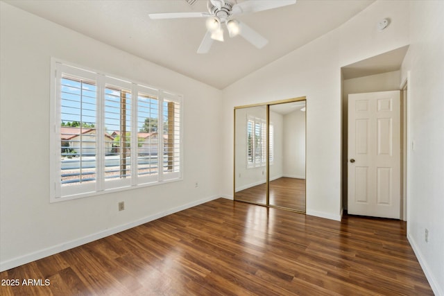 unfurnished bedroom featuring wood finished floors, a closet, baseboards, ceiling fan, and lofted ceiling