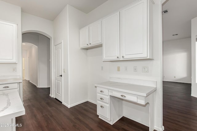 kitchen with white cabinetry, light stone counters, and dark hardwood / wood-style flooring