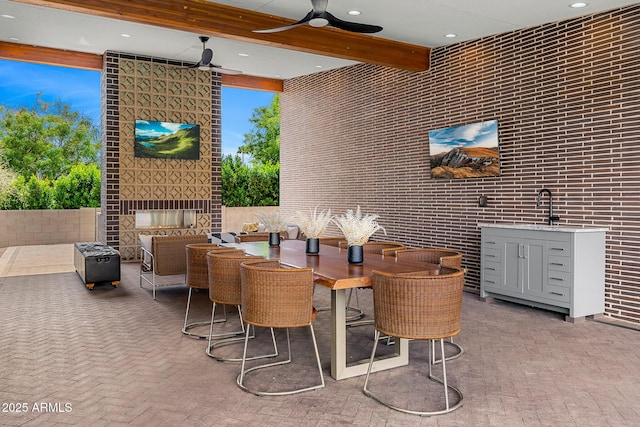 11649 N Miller Rd, Scottsdale, AZ 85260 - dining space with an outdoor brick fireplace, a ceiling fan, brick floor, beamed ceiling, and recessed lighting