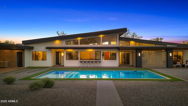 11649 N Miller Rd, Scottsdale, AZ 85260 - back of property at dusk featuring an outdoor pool, stucco siding, central air condition unit, and a patio area