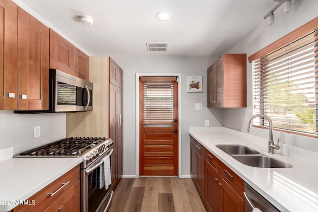 3031 E Avalon Dr, Phoenix, AZ 85016 - kitchen featuring stainless steel appliances, a sink, light wood-style flooring, light countertops, and brown cabinets