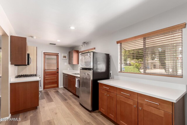 3031 E Avalon Dr, Phoenix, AZ 85016 - kitchen featuring stainless steel appliances, light countertops, light wood-type flooring, recessed lighting, and brown cabinets