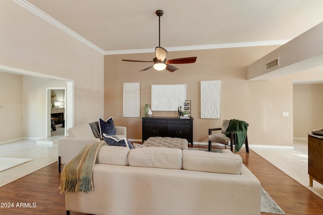 living room with wood-type flooring, crown molding, and ceiling fan