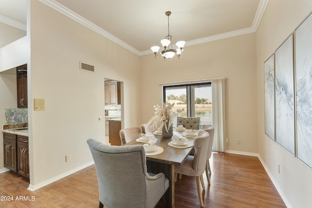 dining space with a notable chandelier, light wood-type flooring, and ornamental molding