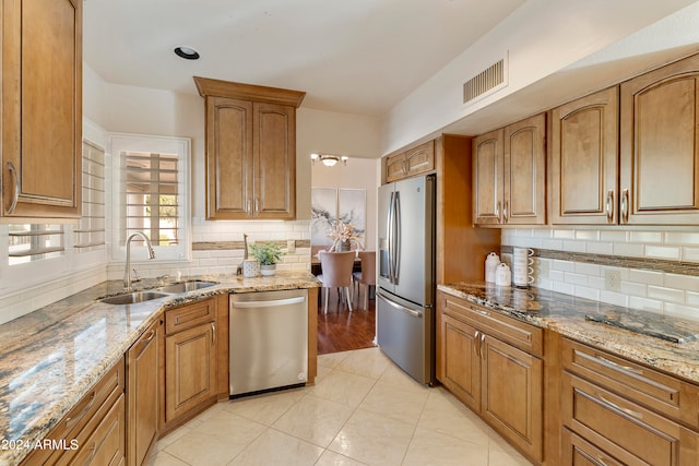 kitchen with light stone counters, tasteful backsplash, sink, appliances with stainless steel finishes, and light tile patterned floors