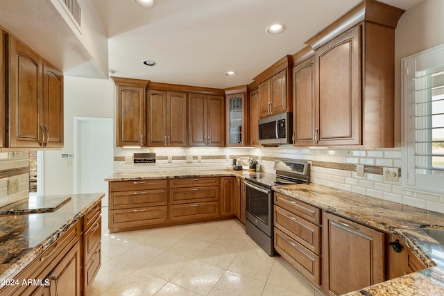 kitchen with light stone counters, appliances with stainless steel finishes, light tile patterned floors, and backsplash