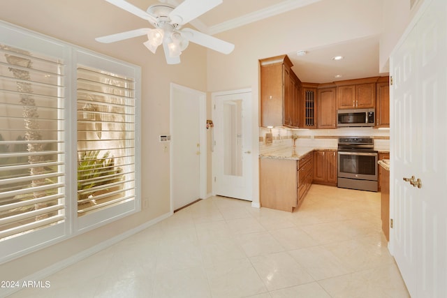 kitchen featuring ceiling fan, light tile patterned floors, stainless steel appliances, light stone countertops, and crown molding