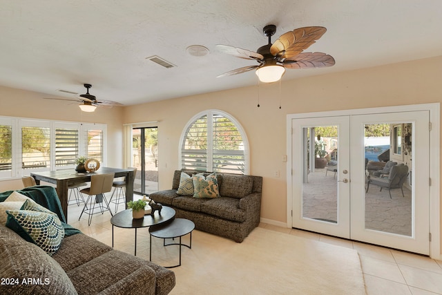 tiled living room with ceiling fan and french doors