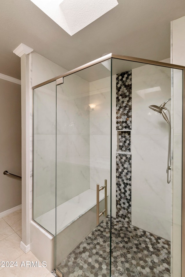 bathroom featuring ornamental molding, a skylight, a shower with door, and tile patterned floors