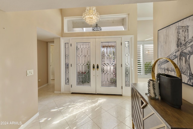 tiled entrance foyer with french doors and a chandelier