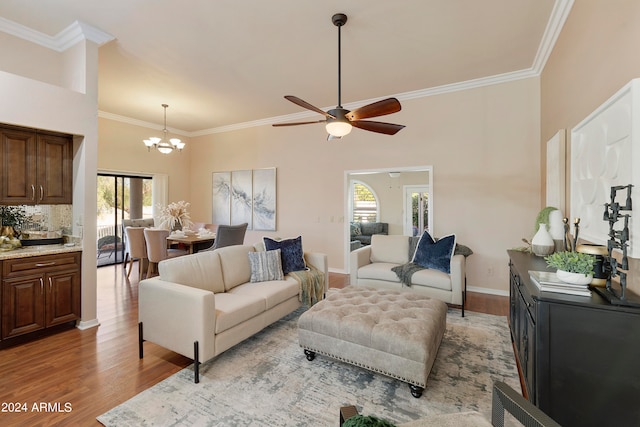 living room with ceiling fan with notable chandelier, light hardwood / wood-style floors, ornamental molding, and plenty of natural light