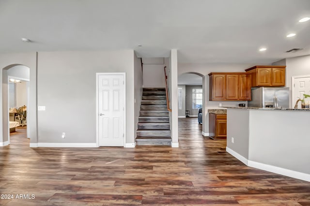 kitchen featuring stainless steel fridge, dark hardwood / wood-style floors, and light stone counters