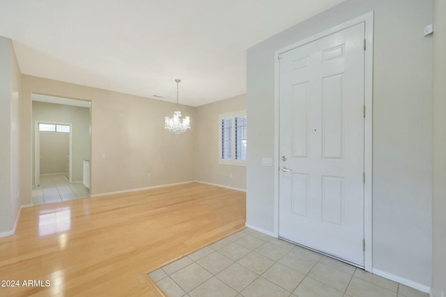 tiled empty room featuring a notable chandelier