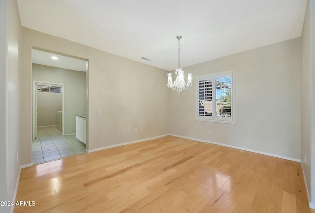 unfurnished room featuring light hardwood / wood-style flooring and a chandelier