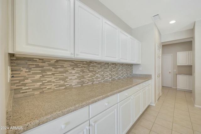 kitchen with backsplash, white cabinetry, light tile patterned floors, and light stone countertops