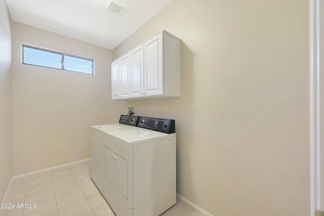 laundry room with washer and clothes dryer, cabinets, and light tile patterned floors