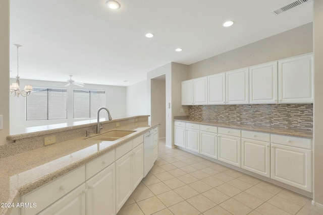 kitchen with decorative backsplash, light stone countertops, sink, pendant lighting, and white cabinets