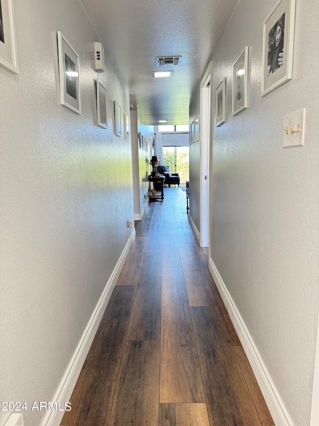 hallway with a textured ceiling and hardwood / wood-style flooring