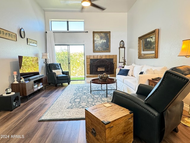 living room with a tiled fireplace, ceiling fan, and dark hardwood / wood-style floors