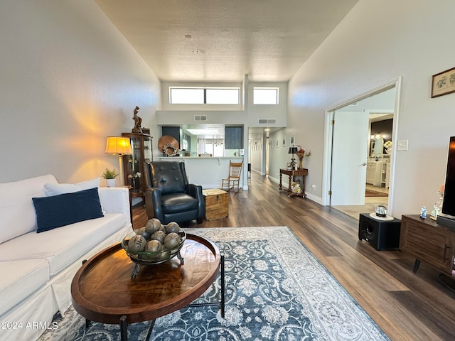 living room with dark hardwood / wood-style floors, a textured ceiling, and a high ceiling