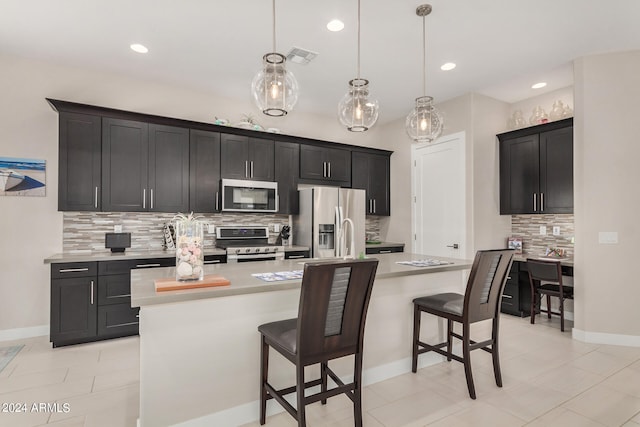 kitchen featuring pendant lighting, stainless steel appliances, a breakfast bar, and a kitchen island with sink