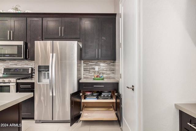 kitchen with appliances with stainless steel finishes, decorative backsplash, dark brown cabinets, and light tile patterned floors