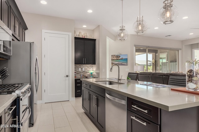 kitchen featuring appliances with stainless steel finishes, backsplash, pendant lighting, a kitchen island with sink, and sink