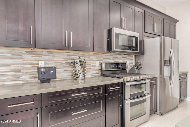 kitchen with dark brown cabinetry, stainless steel appliances, light tile patterned floors, and decorative backsplash