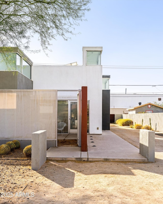 rear view of property featuring a patio, fence, and stucco siding