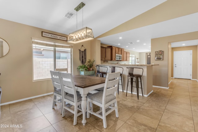 dining space with lofted ceiling and light tile patterned flooring