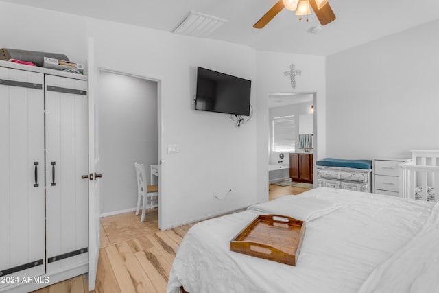 bedroom with ceiling fan, ensuite bathroom, and light wood-type flooring