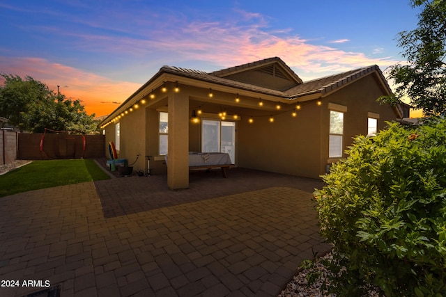 back house at dusk featuring a patio area