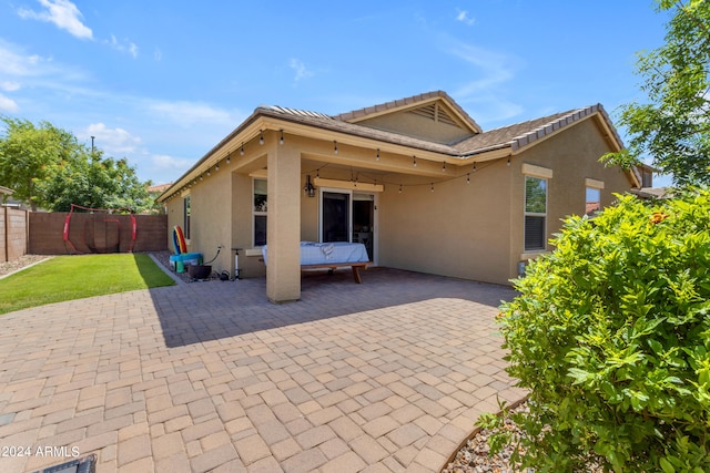 back of property with a patio area and a lawn