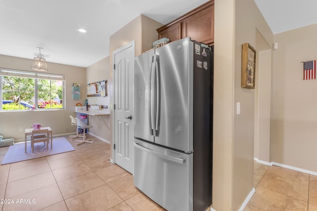 kitchen featuring pendant lighting, stainless steel refrigerator, and light tile patterned flooring