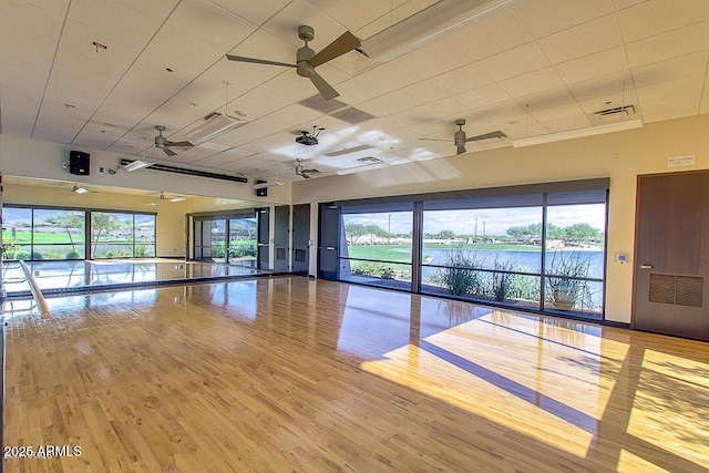 spare room with a water view, a healthy amount of sunlight, ceiling fan, and light hardwood / wood-style flooring