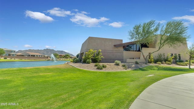 view of side of home with a water and mountain view and a lawn