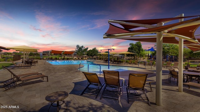 pool at dusk with a patio area