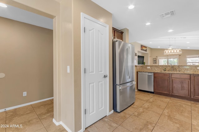 kitchen featuring appliances with stainless steel finishes, lofted ceiling, sink, hanging light fixtures, and light tile patterned floors