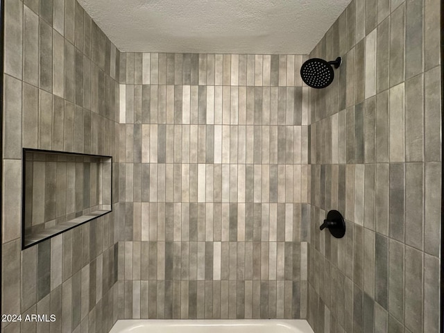 bathroom featuring a textured ceiling and tiled shower