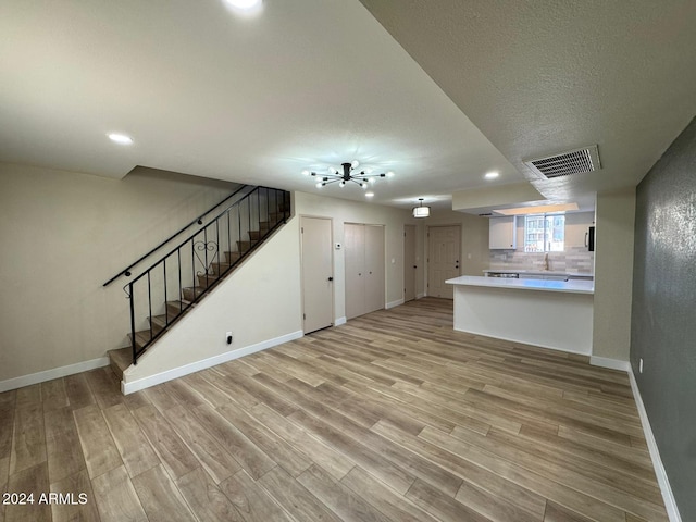 unfurnished living room with light wood-type flooring and a textured ceiling