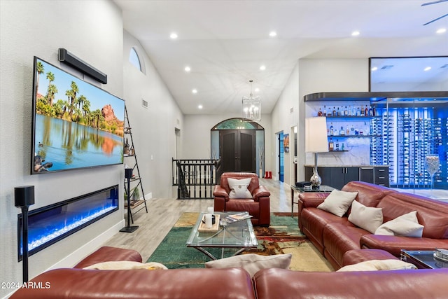 living room with light hardwood / wood-style flooring, high vaulted ceiling, and an inviting chandelier