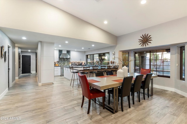 dining space with light wood-type flooring and high vaulted ceiling