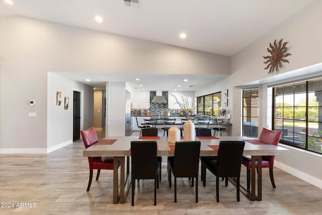 dining space with light hardwood / wood-style flooring, high vaulted ceiling, and a healthy amount of sunlight