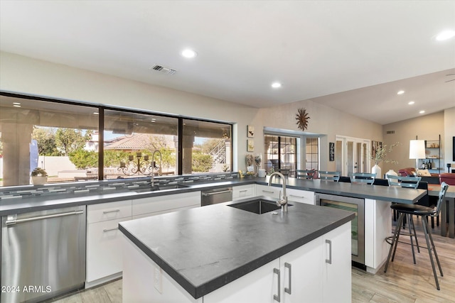24218 N 85th St, Scottsdale, AZ 85255 - kitchen with stainless steel dishwasher, beverage cooler, dark countertops, a center island with sink, and light wood finished floors