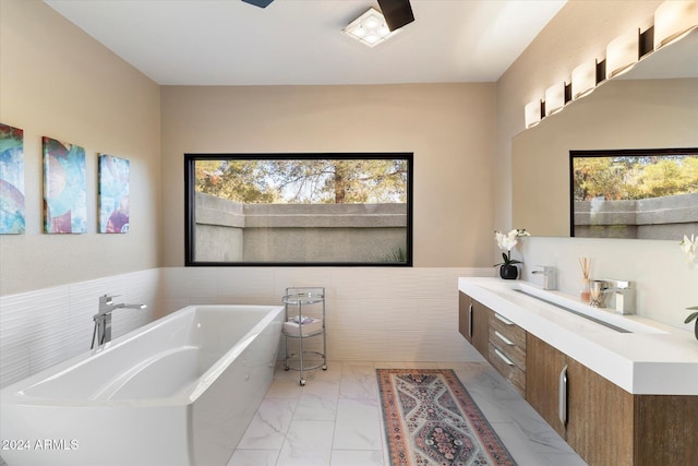 24218 N 85th St, Scottsdale, AZ 85255 - bathroom featuring a soaking tub, marble look tile flooring, vanity, tile walls, and a wainscoted wall