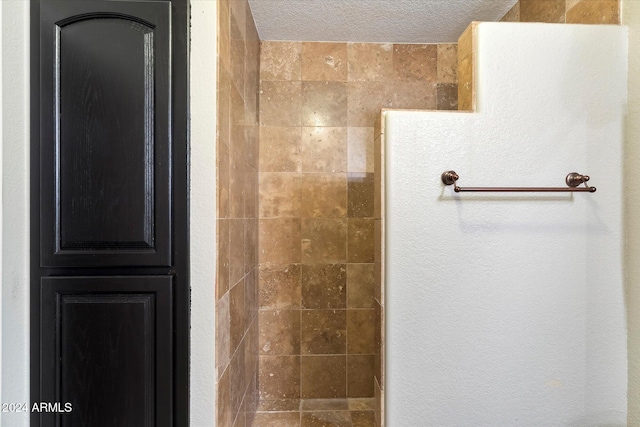 bathroom with a tile shower and a textured ceiling