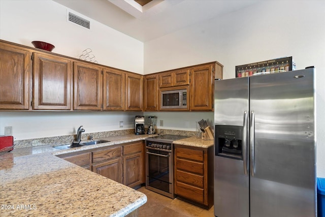 kitchen with appliances with stainless steel finishes, light stone counters, and sink