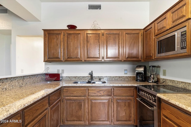 kitchen featuring sink, light stone countertops, and stainless steel appliances